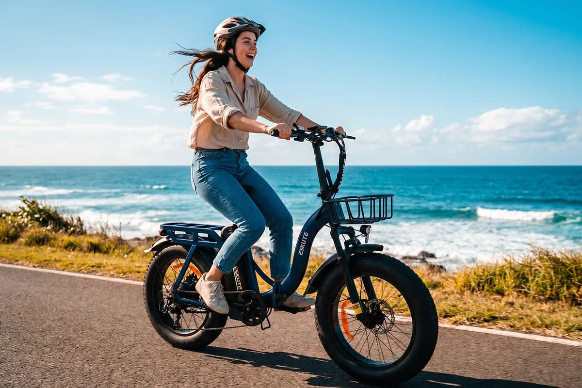 Frau fährt das Eskute D202 E-Bike entlang einer Küstenstraße mit Meerblick