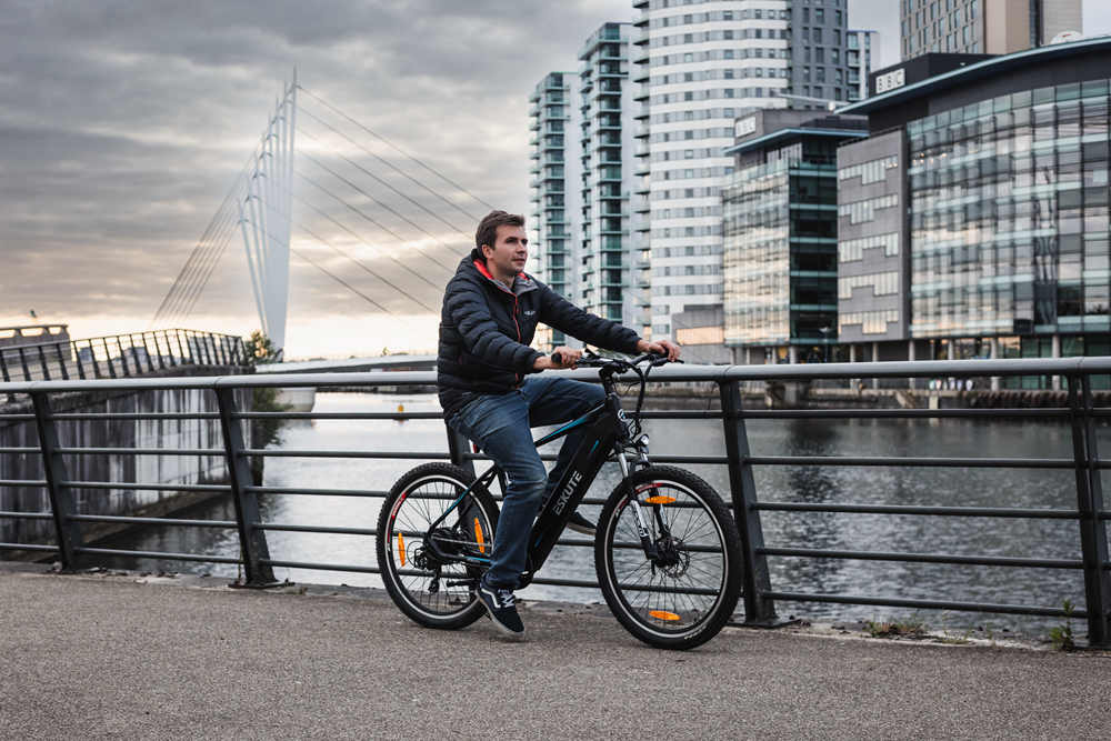 ein mann fährt mit seinem e bike am fluss in der stadt