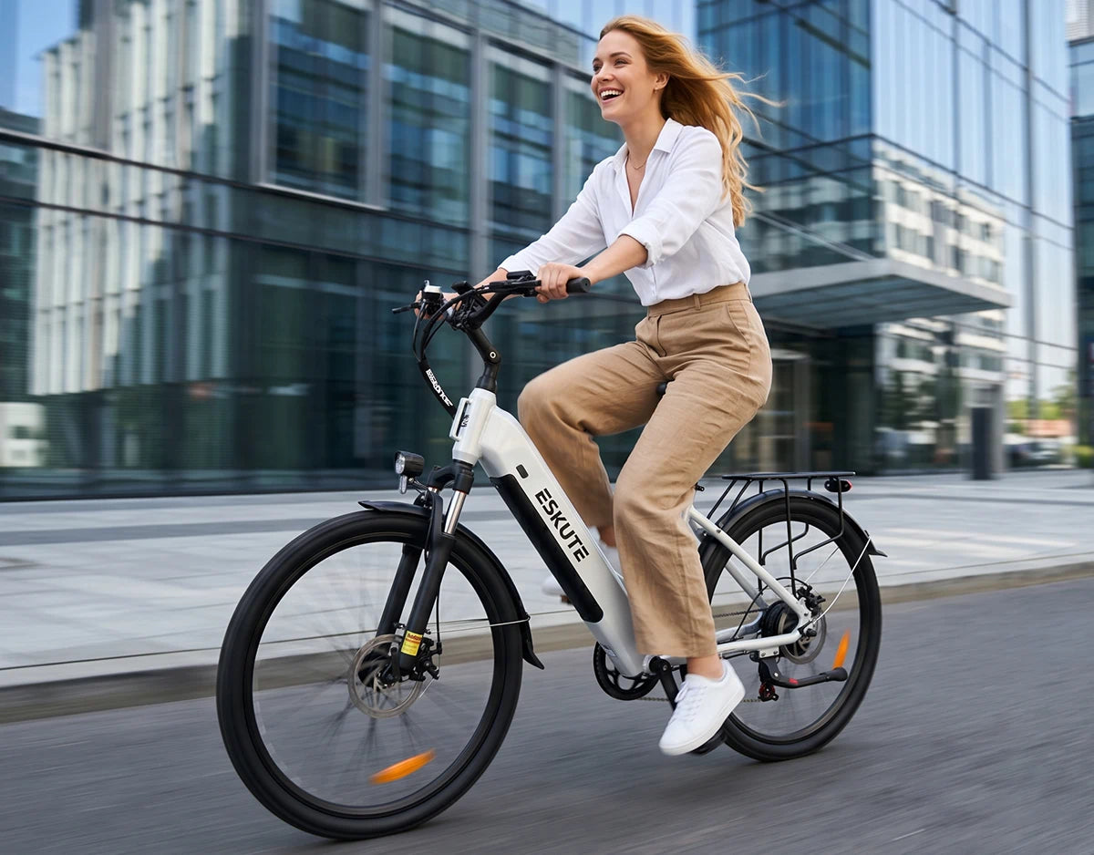 [Color:Weiß]Frau fährt mit dem weißen Eskute C202 City-E-Bike vor modernen Wolkenkratzern zur Arbeit.